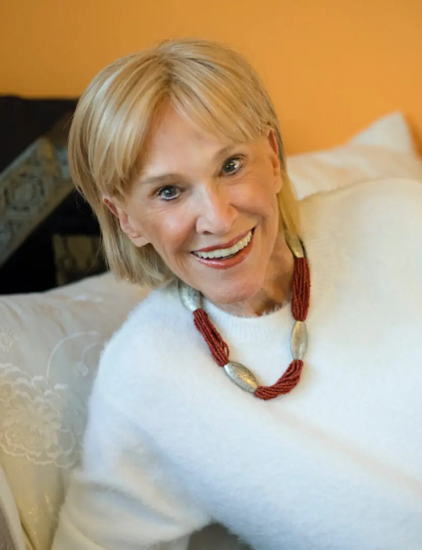 A woman sitting on top of a couch wearing a white sweater.