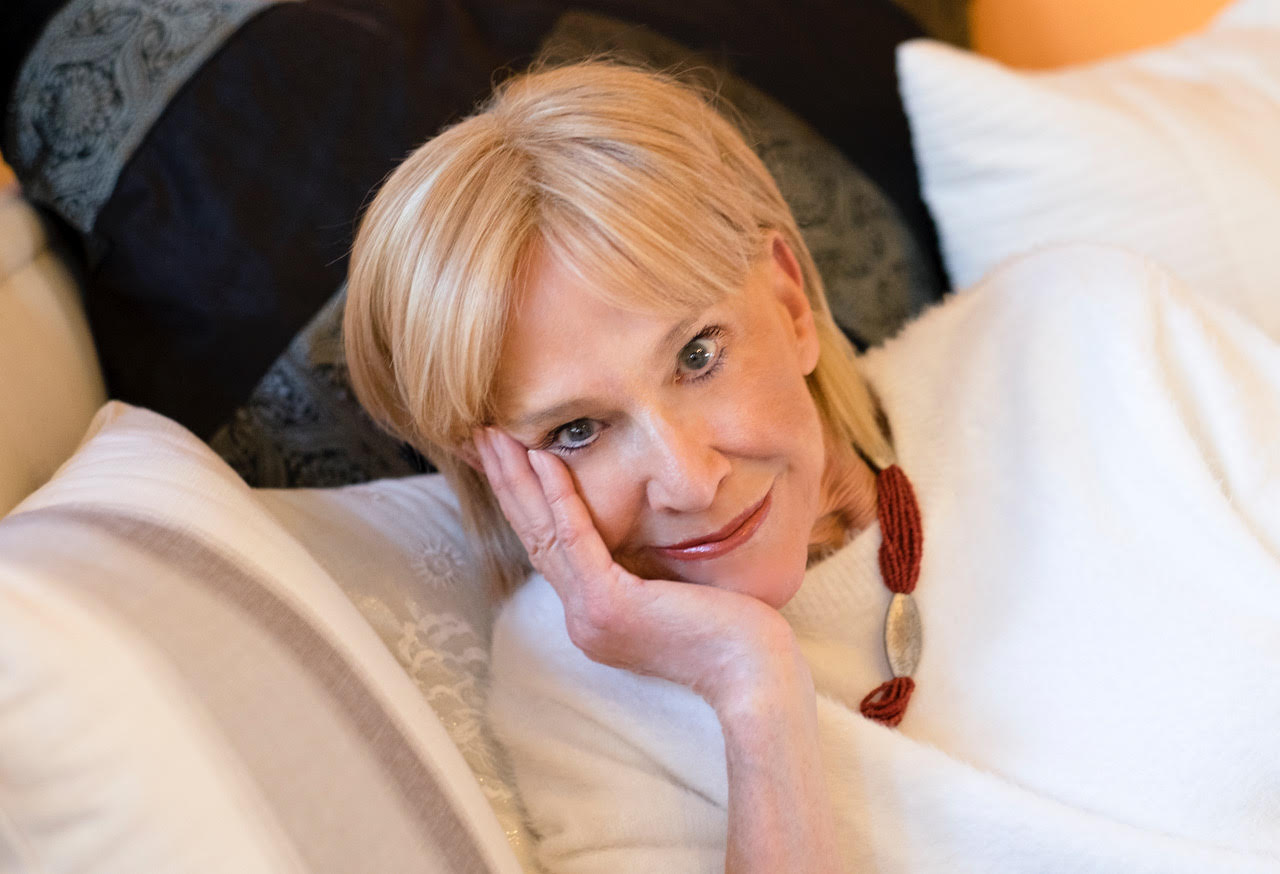 A woman laying in bed with her hand on the face.