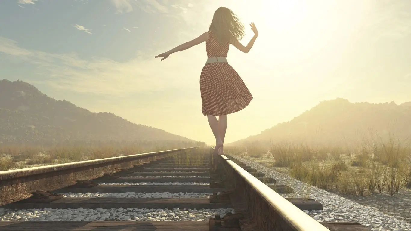 A woman is walking on the train tracks