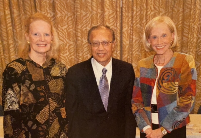 Three people standing next to each other in front of a curtain.